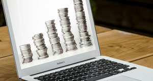 image of laptop with image of increasingly large stacks of coins